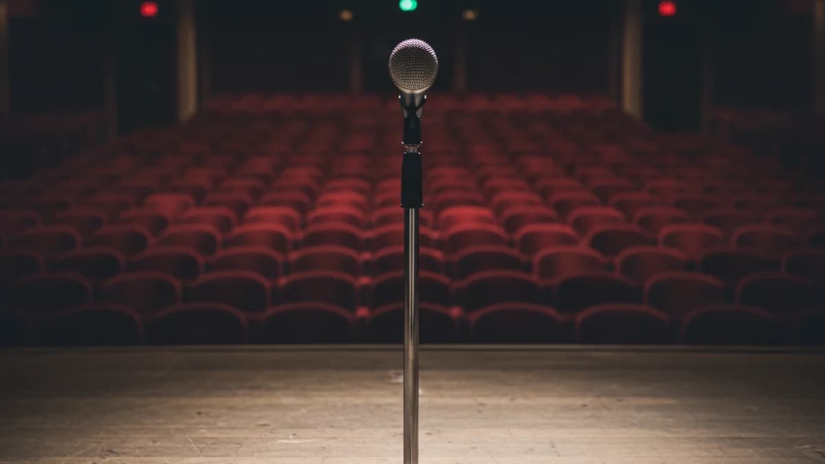 Micròfon en un escenari buit o un cartell d'esdeveniment ajornat, simbolitzant la suspensió del concert.