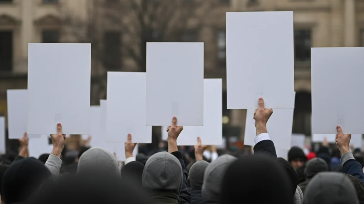 Imatge genèrica d'una protesta laboral amb pancartes a una plaça urbana, amb figures borroses.