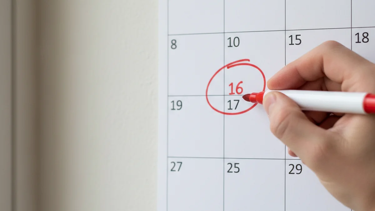 Imatge genèrica d'una mà marcant dates importants en un calendari de paret.