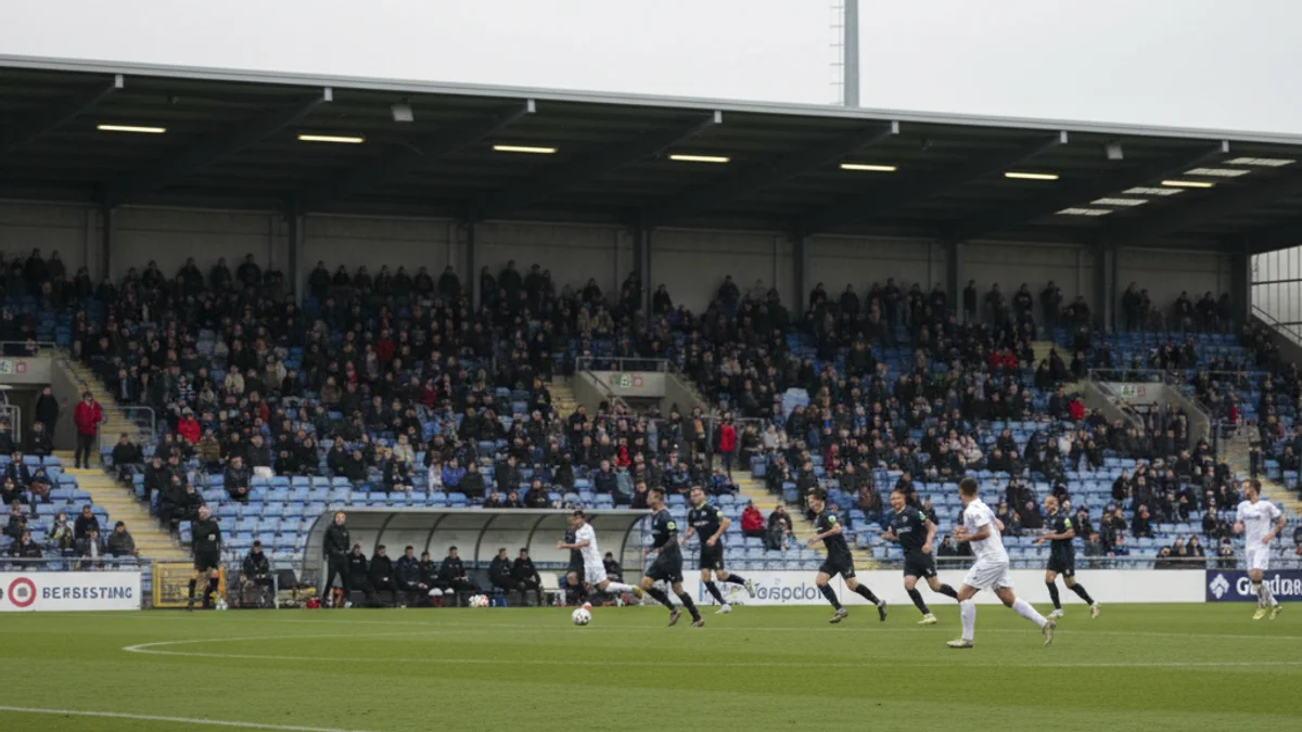 Vista general d'un partit de futbol a l'estadi de Montilivi, amb gespa verda i figures borroses d'esportistes.