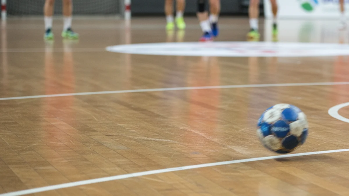 Imatge genèrica d'un partit d'handbol amb jugadores en acció i la pilota al centre de la pista.