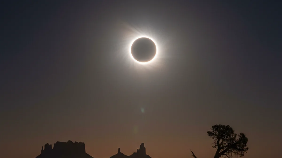Representació visual d'un eclipsi solar híbrid amb l'anell de foc visible al voltant de la Lluna.