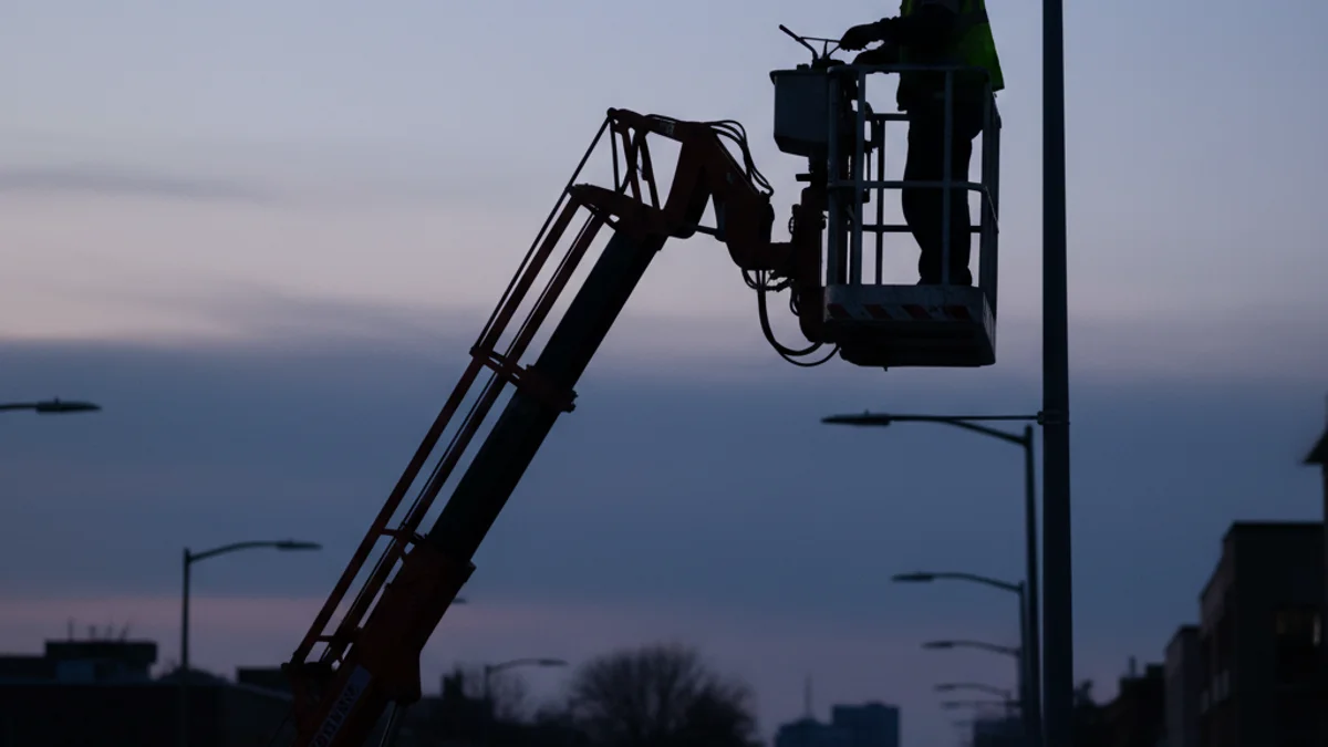 Imatge genèrica d'un operari treballant en el manteniment de l'enllumenat públic en un carrer de nit.