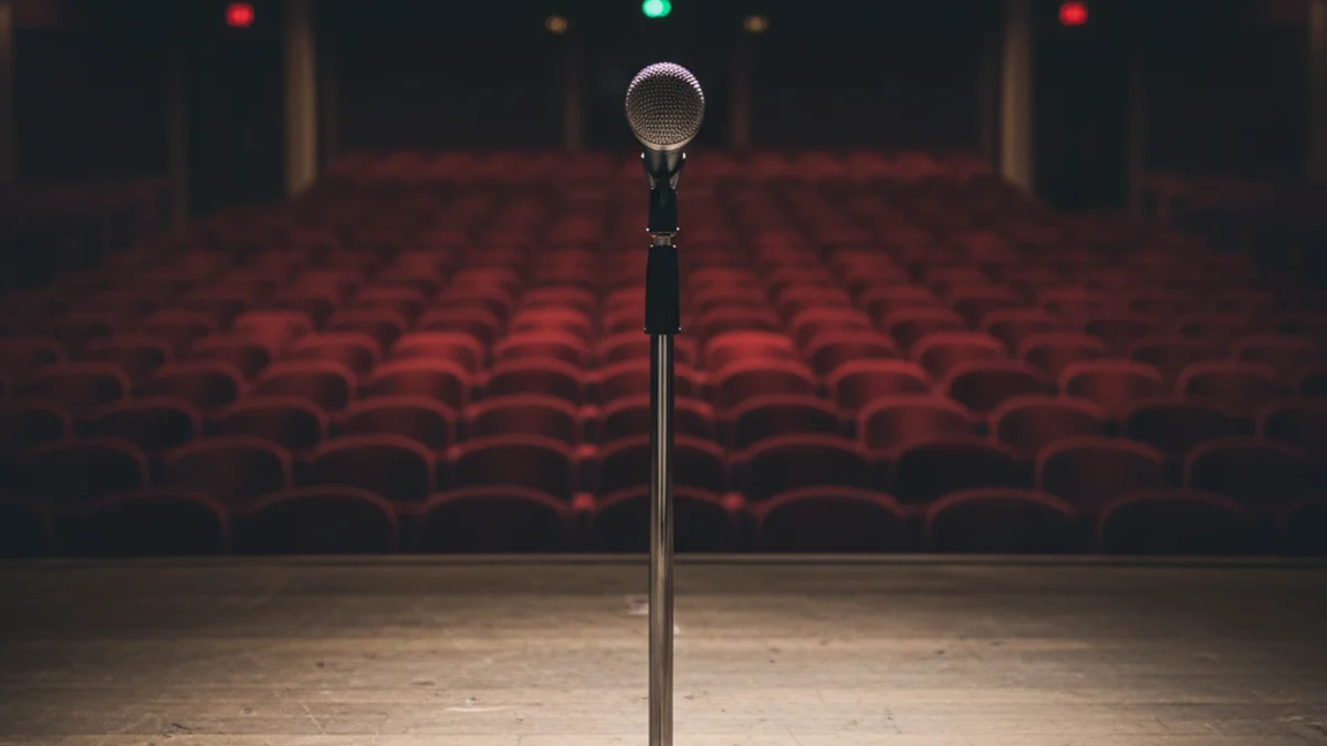 Micròfon en un escenari buit o un cartell d'esdeveniment ajornat, simbolitzant la suspensió del concert.