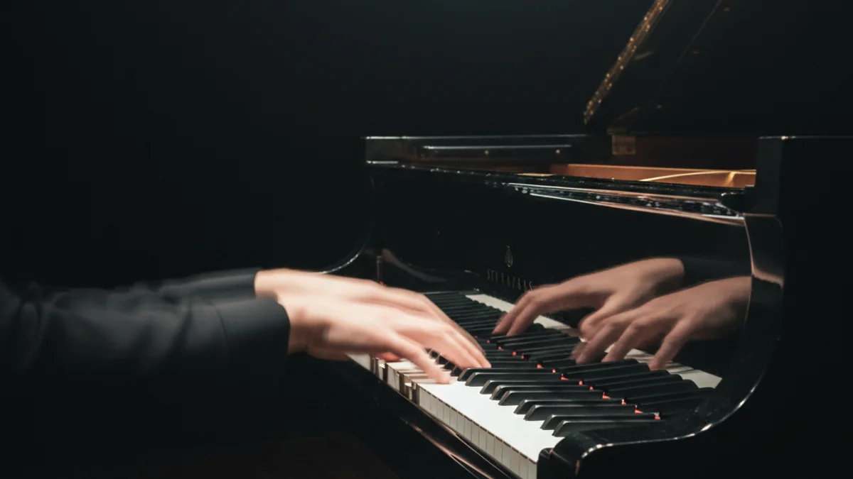 Imatge d'un piano de cua en un escenari íntim, amb les mans d'un músic tocant les tecles.