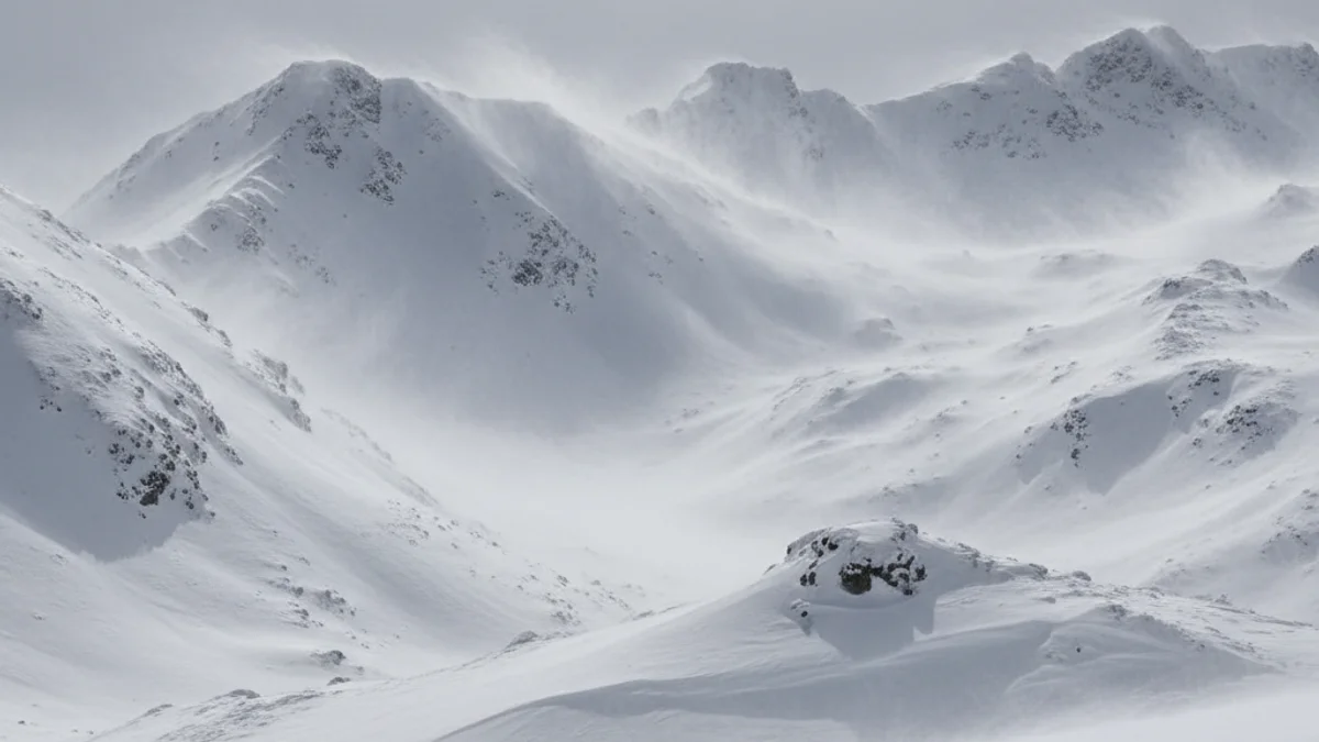 Vista d'un paisatge muntanyós cobert per una gran nevada recent, amb indicis de ventisca.
