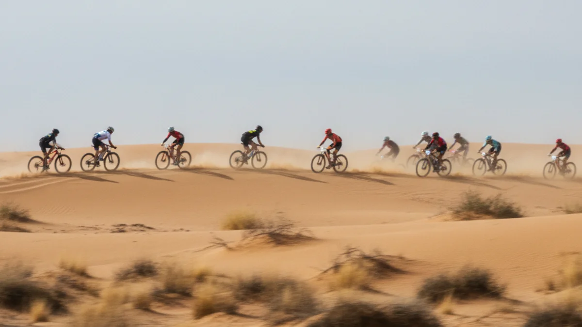 Imatge genèrica de ciclistes de muntanya travessant dunes de sorra durant una cursa al desert.
