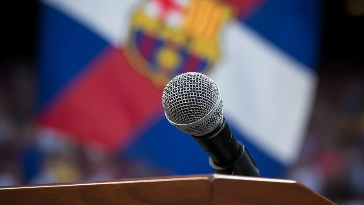 Imatge genèrica d'una roda de premsa esportiva amb un micròfon i un fons amb els colors del club.