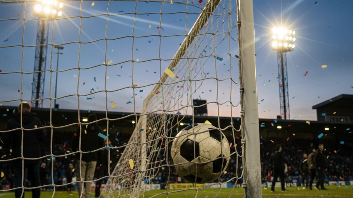 Imatge generica d'una pilota de futbol dins la porteria durant un partit nocturn.