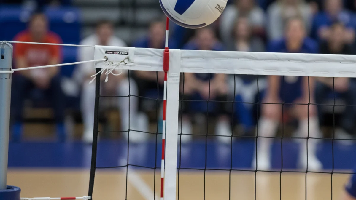 Una pilota de voleibol sobre la xarxa durant un partit intens en un pavelló esportiu.