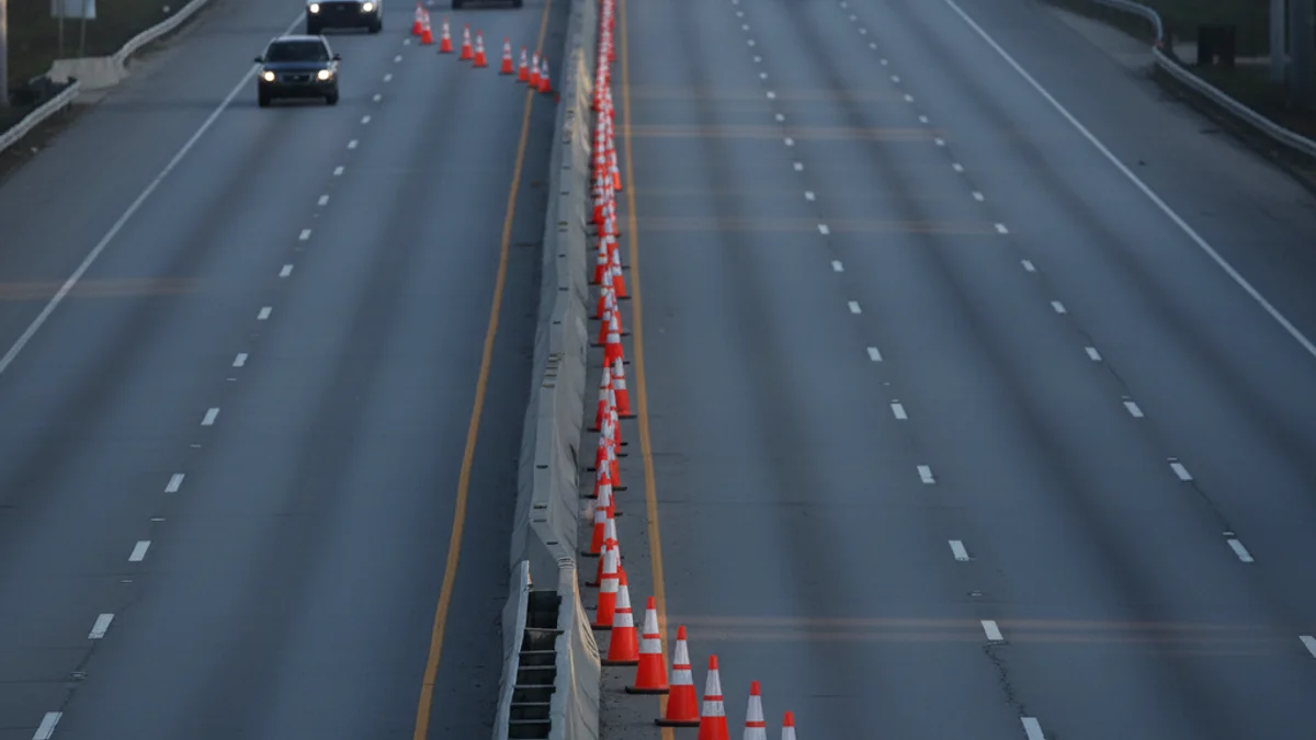 Imatge d'una carretera tallada amb cons de trànsit i llums d'emergència.
