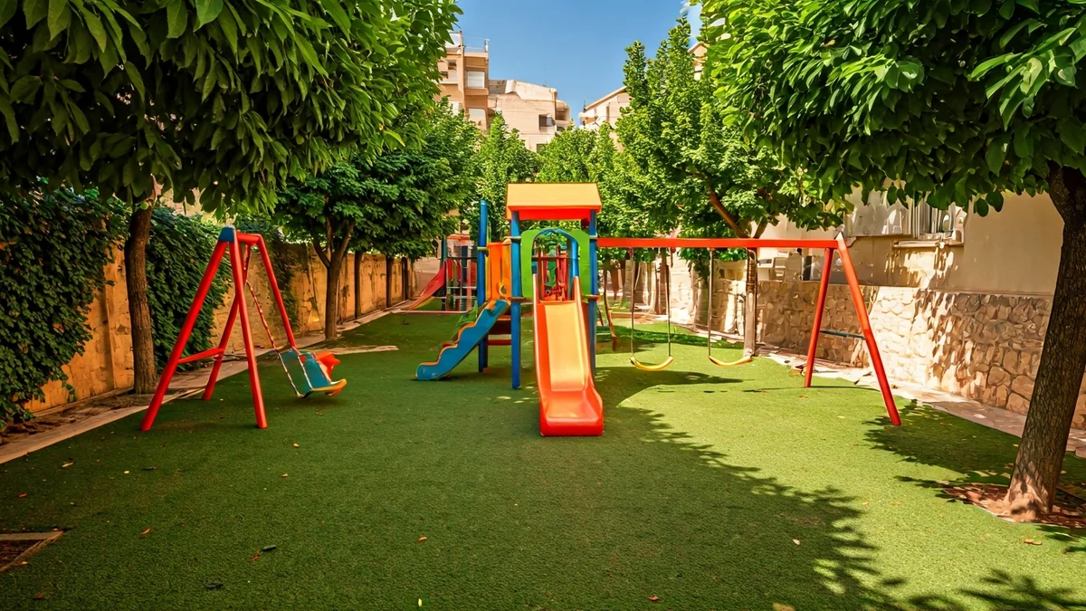 Generic image of a renovated children's playground with games and vegetation in an urban space.