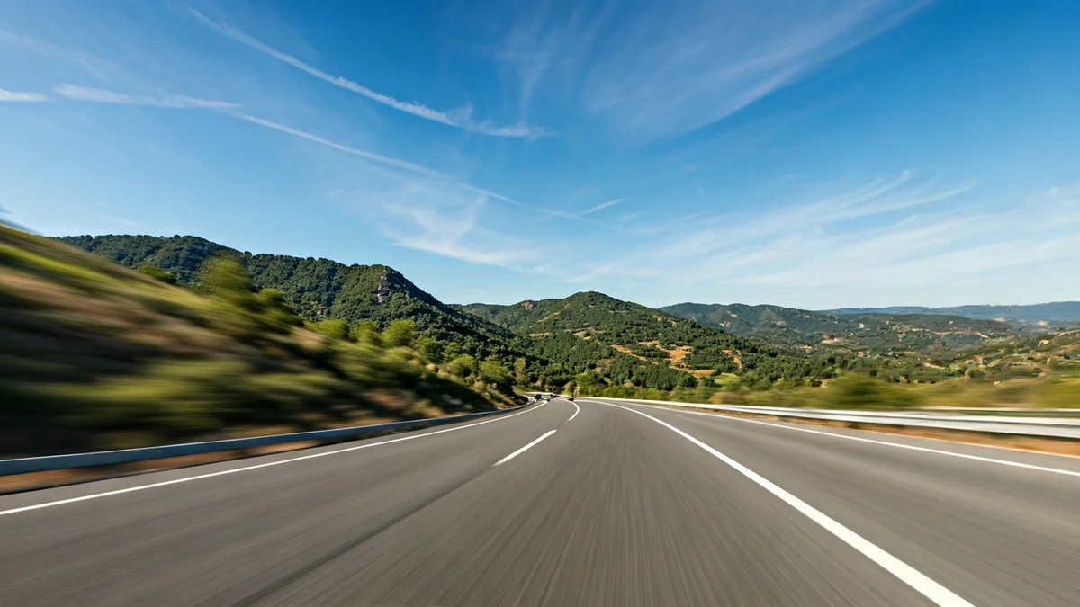 Imatge genèrica d'una carretera que travessa un paisatge muntanyós català, amb turons verds i cel blau.
