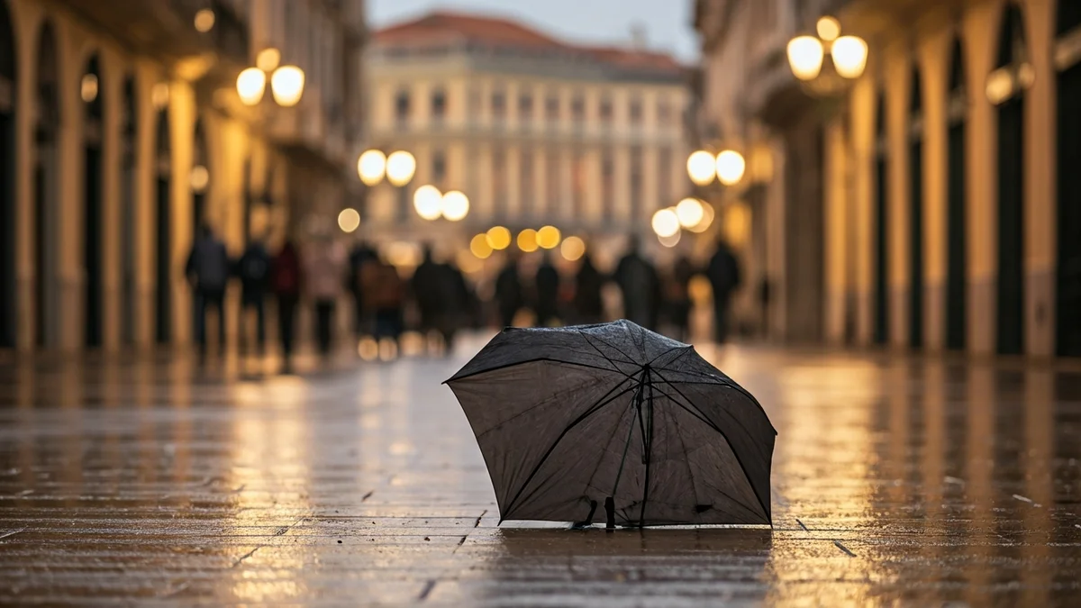 Generic image of an open umbrella on a wet street, with blurred lights in the background, suggesting light rain.