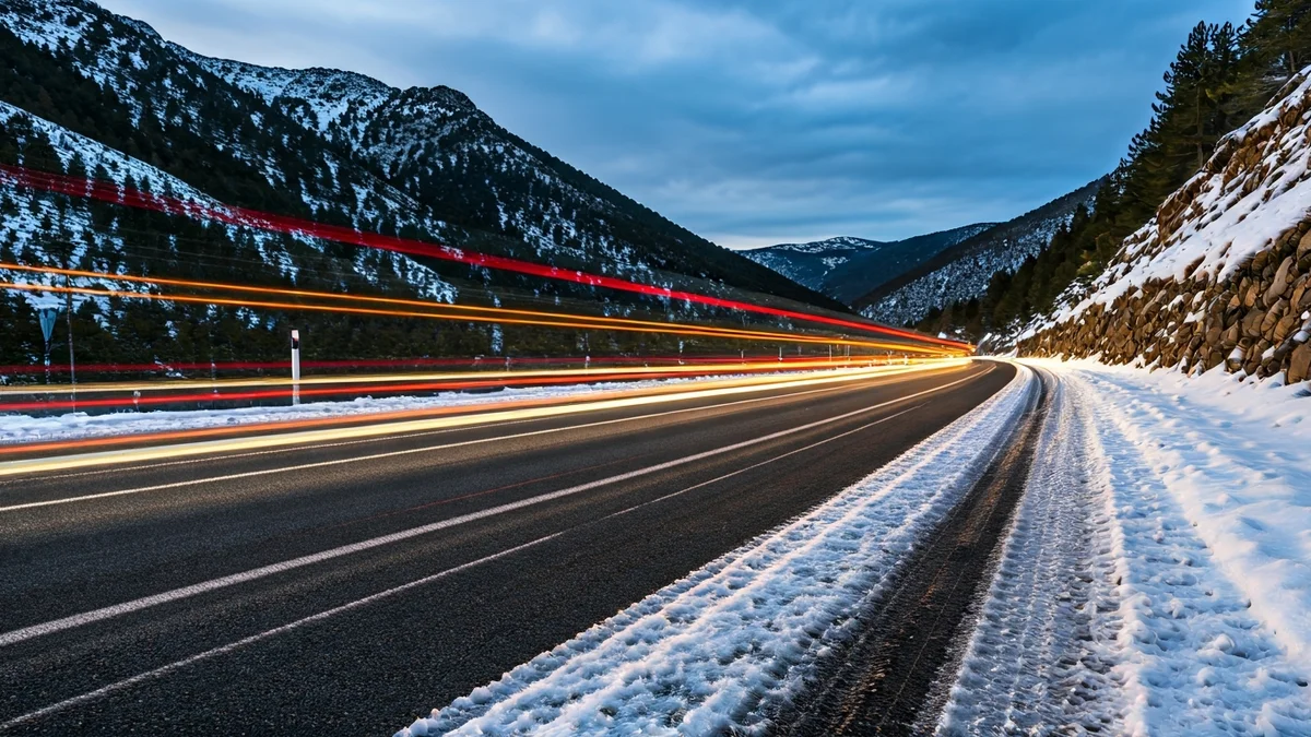Imatge genèrica d'una carretera de muntanya nevada amb cadenes, en un dia fred.