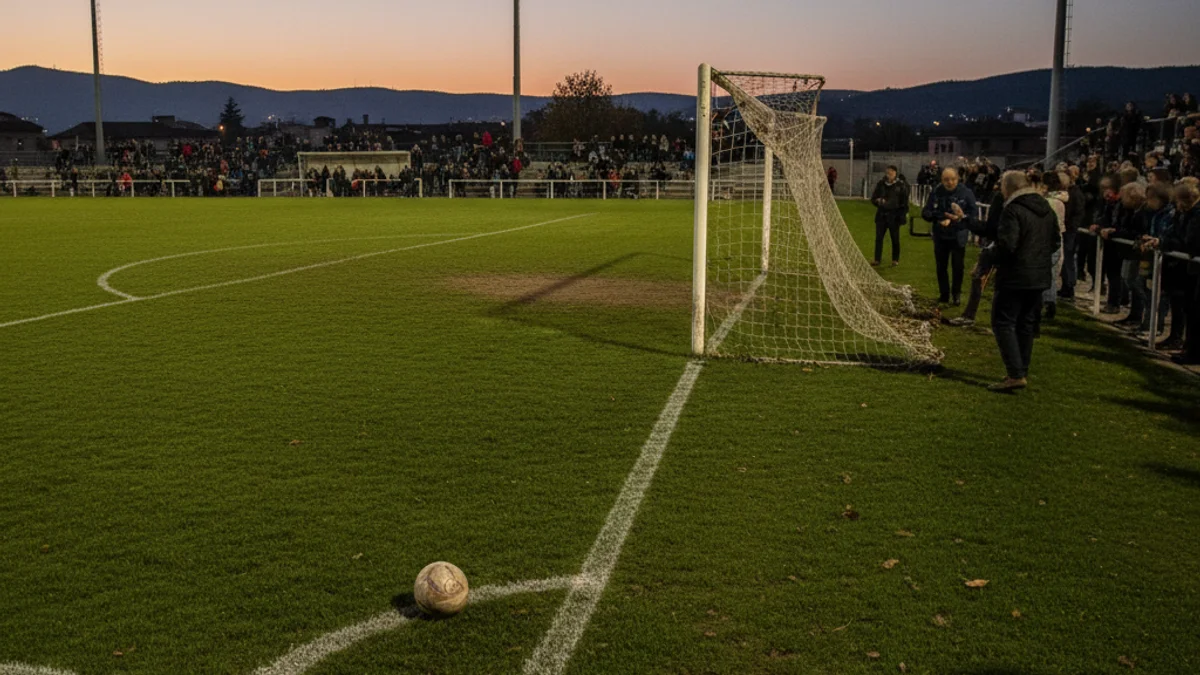 Imatge genèrica d'una pilota de futbol sobre la gespa d'un camp municipal durant el capvespre.