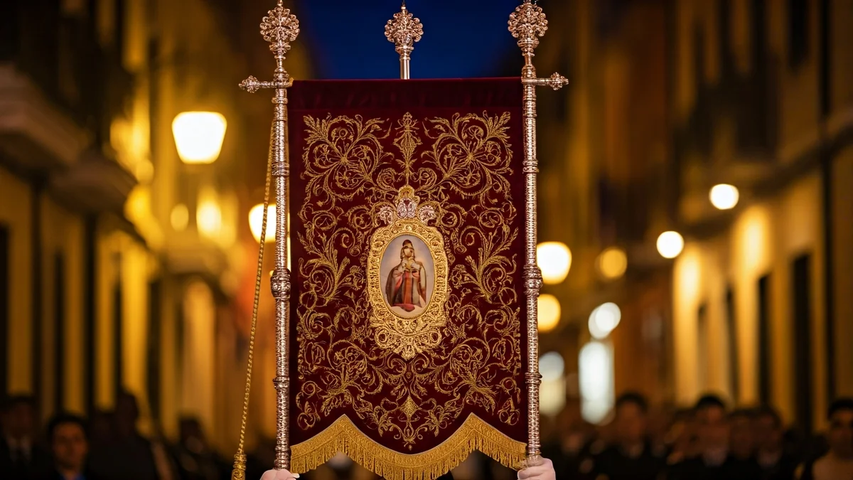 Imatge genèrica d'un estendard de processó religiosa amb detalls brodats, sostingut per mans en un carrer al capvespre.