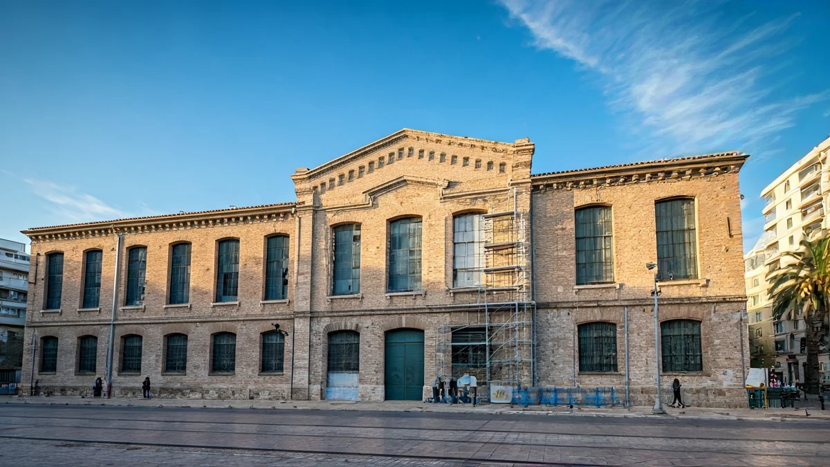 Imatge genèrica de la façana d'un edifici industrial històric en rehabilitació, amb bastides sent retirades.