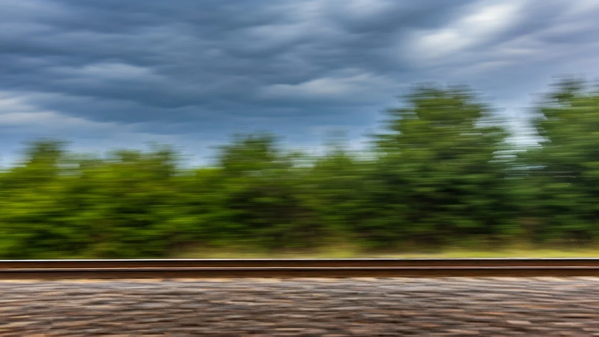 Generic image of train tracks under a stormy sky, with strong wind blowing.