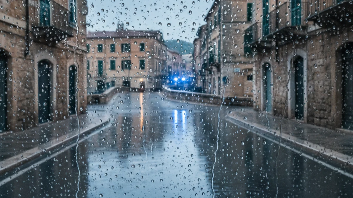 Generic image of rain falling on city asphalt under a cloudy sky.