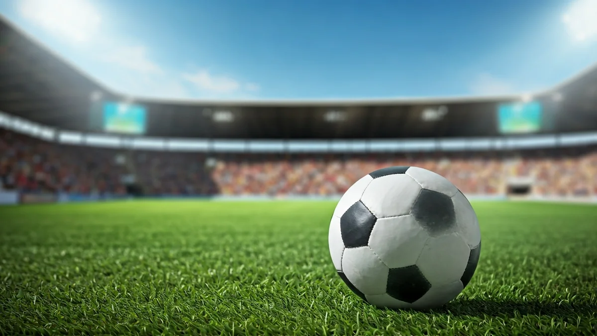 Imagen genérica de un balón de fútbol en un campo verde con público difuminado al fondo.
