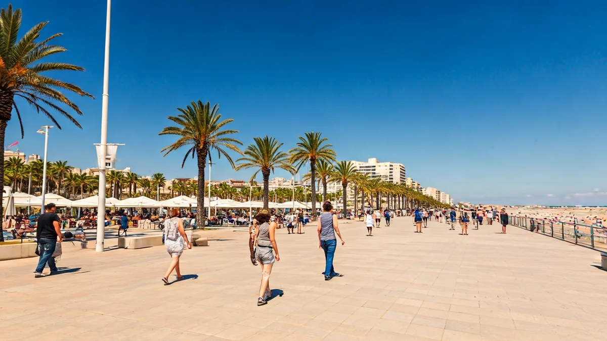 Imagen genérica de un paseo marítimo concurrido en verano, con palmeras y cielo azul.