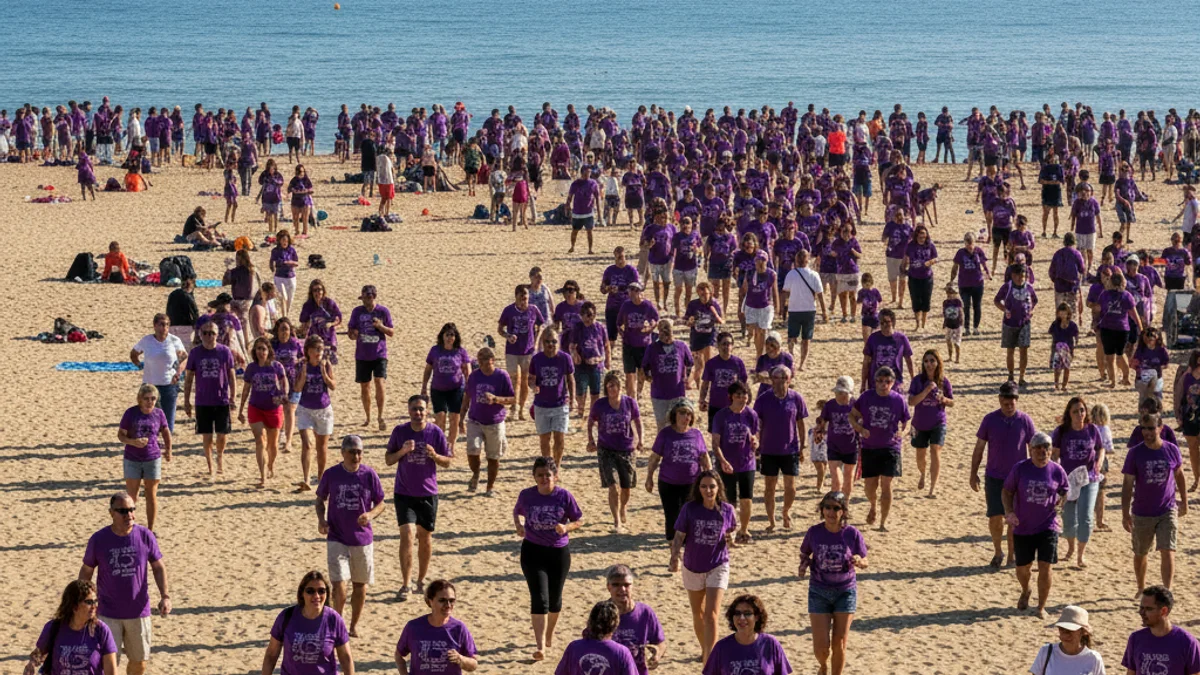 Imatge genèrica d'una multitud amb samarretes violetes participant en una jornada solidària a la platja.