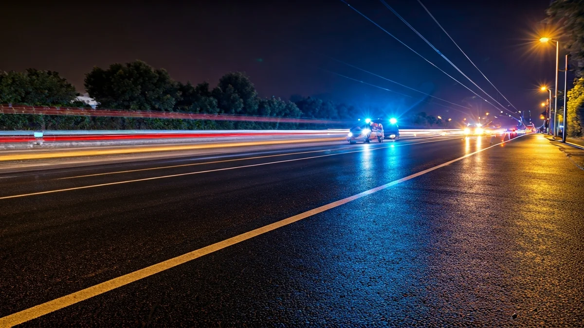 Imatge genèrica de llums d'emergència reflectint-se sobre l'asfalt mullat amb vies de tren al fons, simbolitzant una interrupció del servei ferroviari per condicions meteorològiques adverses.