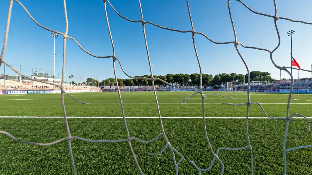Porteria de futbol amb la xarxa trencada i marques de rodes a la gespa