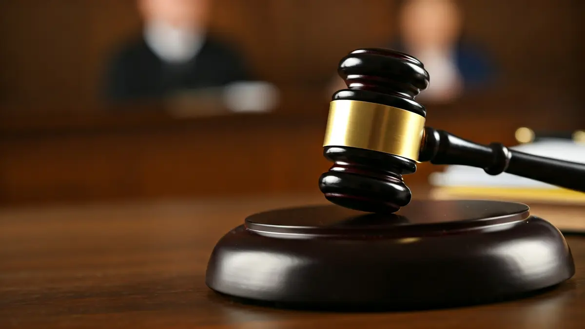 Imatge genèrica d'un martell de jutge sobre una taula de fusta en un jutjat.