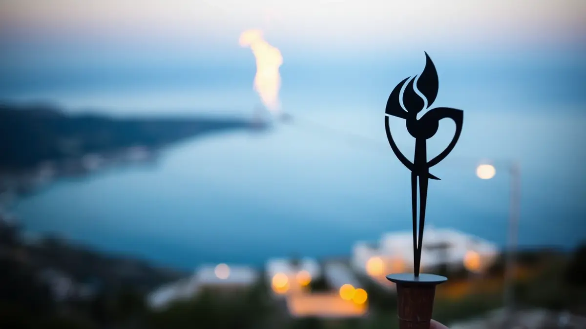 Imatge genèrica d'una flama, símbol del Correllengua Agermanat, amb un paisatge mediterrani de fons.