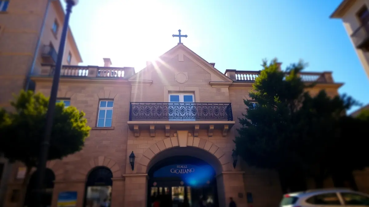 Town hall facade with wrought iron balcony under sunlight.