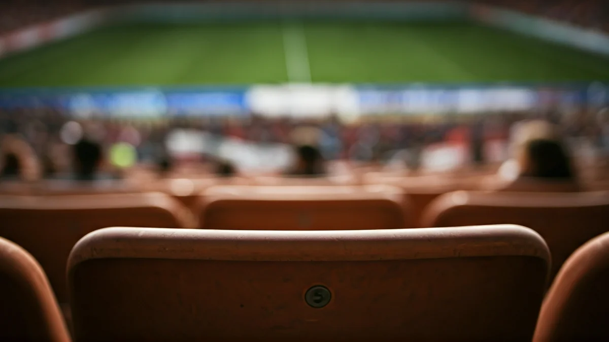 Generic image of an empty soccer stadium seat with a blurred crowd in the background.