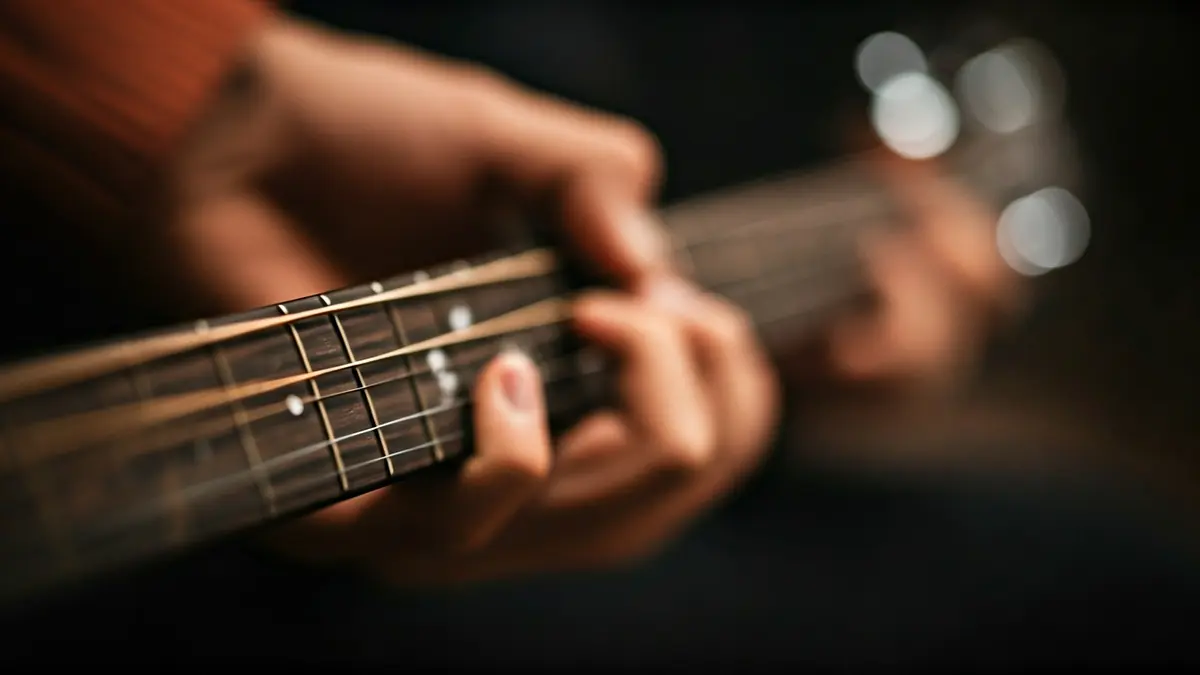 Imatge genèrica d'unes mans tocant una guitarra acústica.