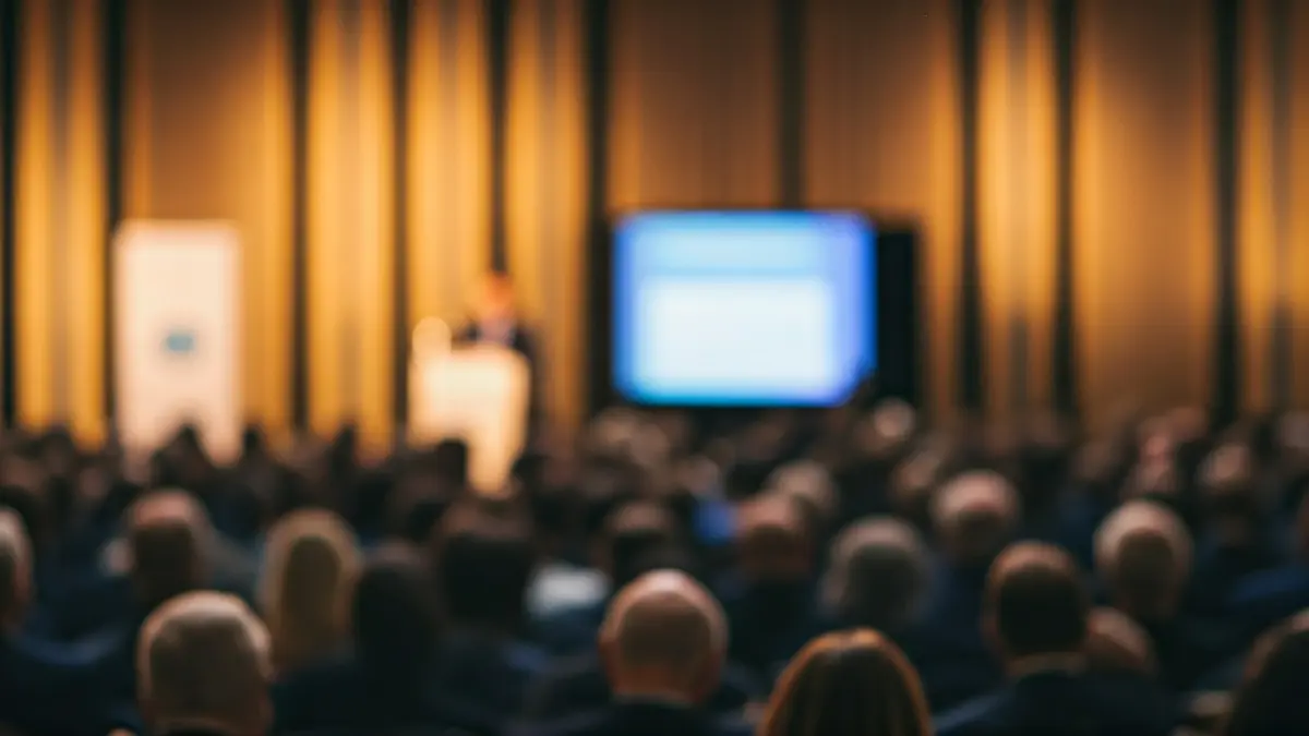 Imagen genérica de una conferencia o jornada con un ponente y público asistente.