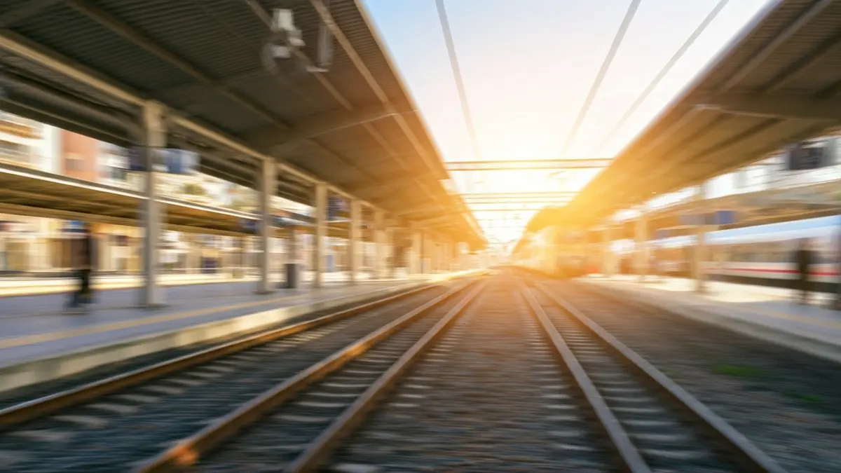 Generic image of a train station with tracks and a train in the distance.