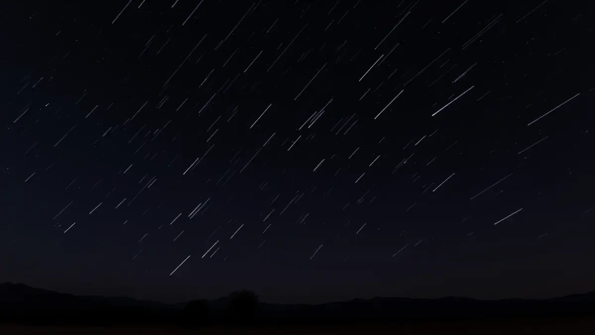 Generic image of a meteor shower in a dark night sky.