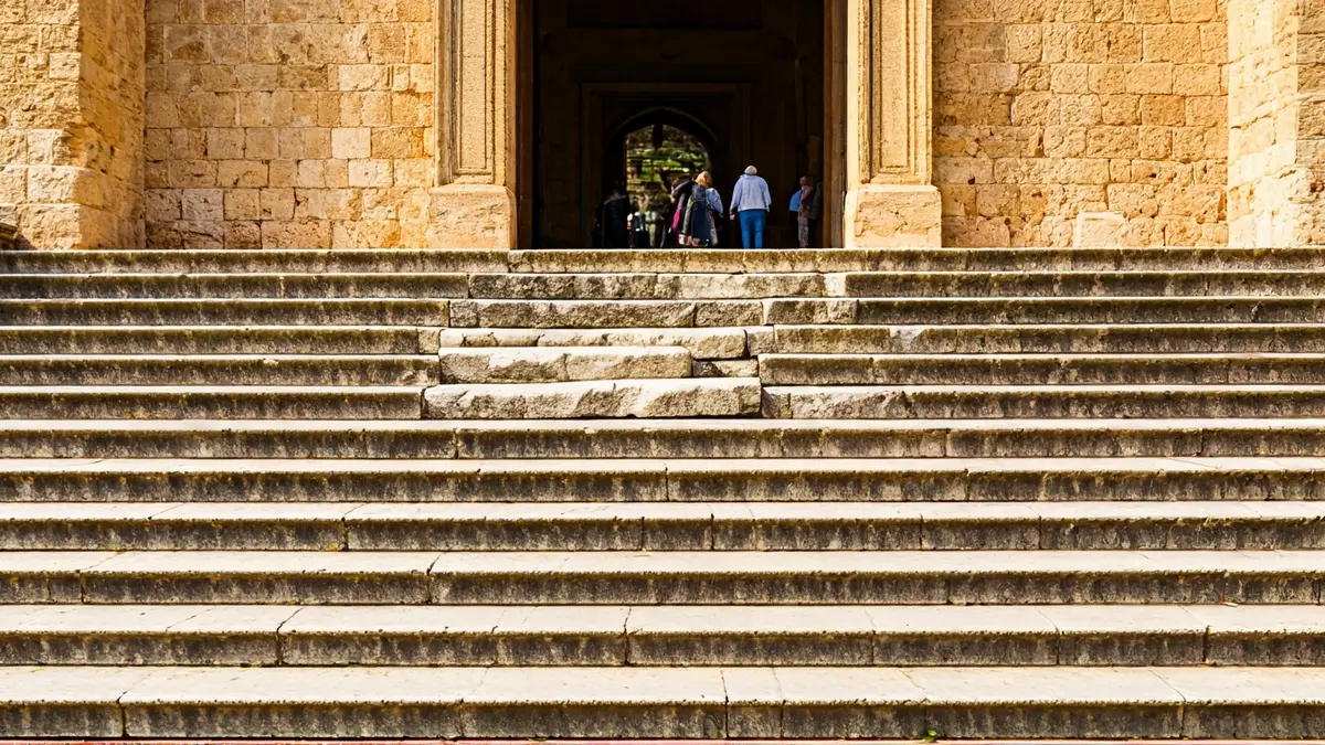 Escalinata de piedra con escalones desencajados en la entrada de un monumento antiguo.