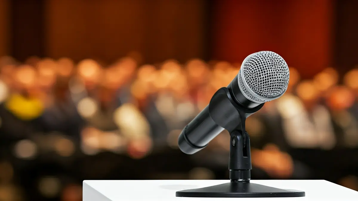 Imatge genèrica d'un podi amb un micròfon en una sala de conferències, representant una presentació de recerca.