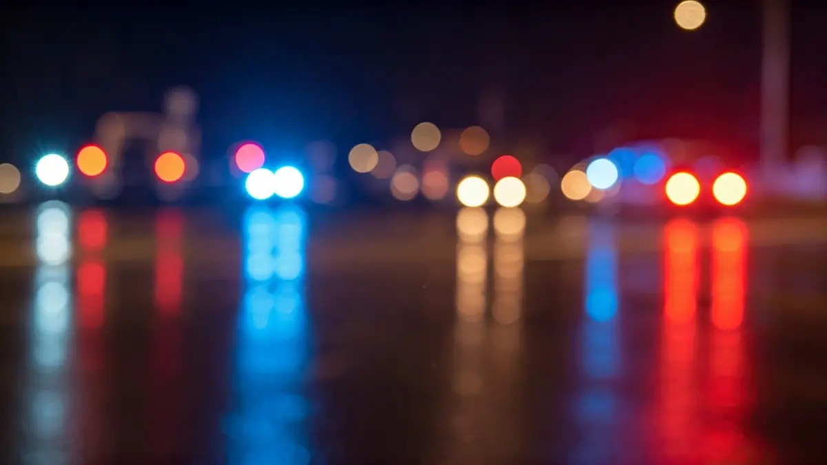 Imatge genèrica de llums d'emergència reflectint-se sobre asfalt mullat de nit.