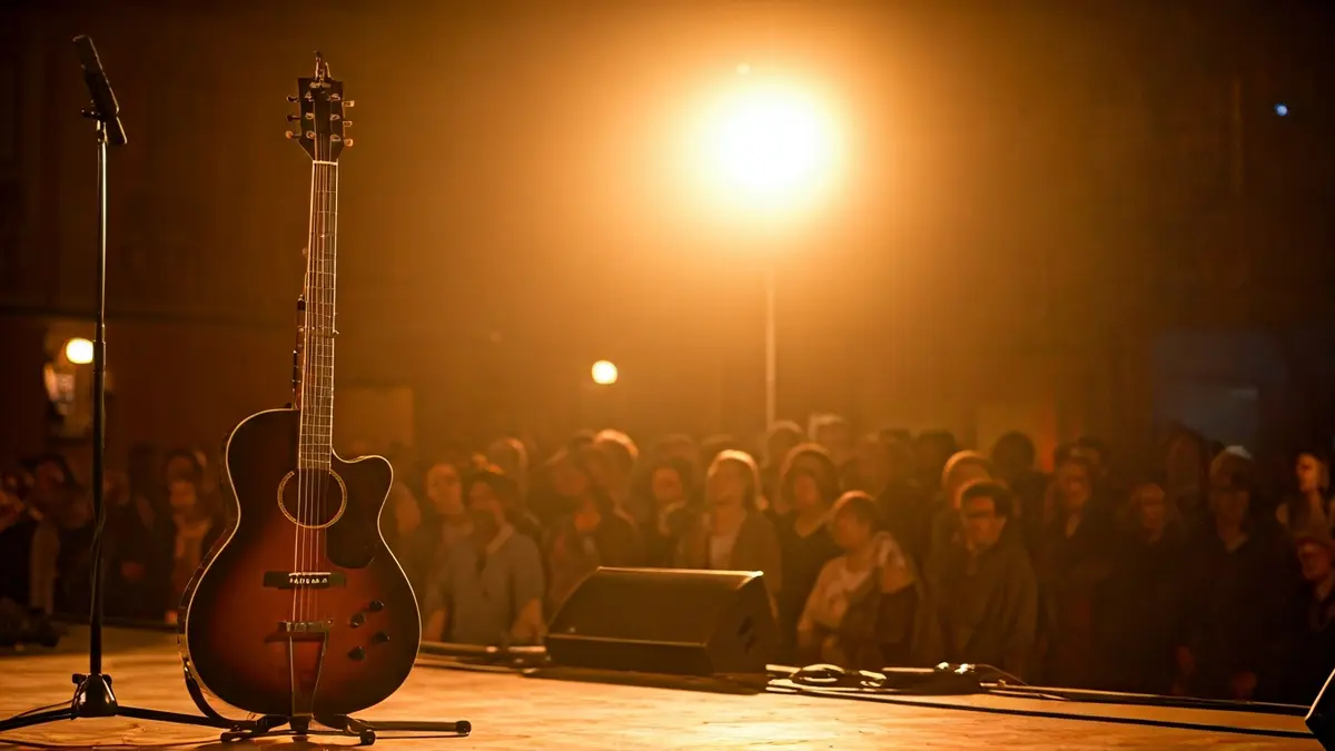 Generic image of an acoustic guitar on a stage with a spotlight, with a blurred audience in the background.