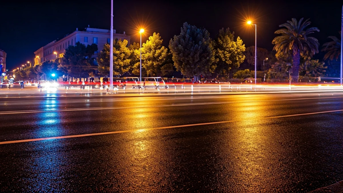 Imagen genérica de luces de emergencia reflejándose sobre el asfalto mojado en una carretera con tráfico nocturno.