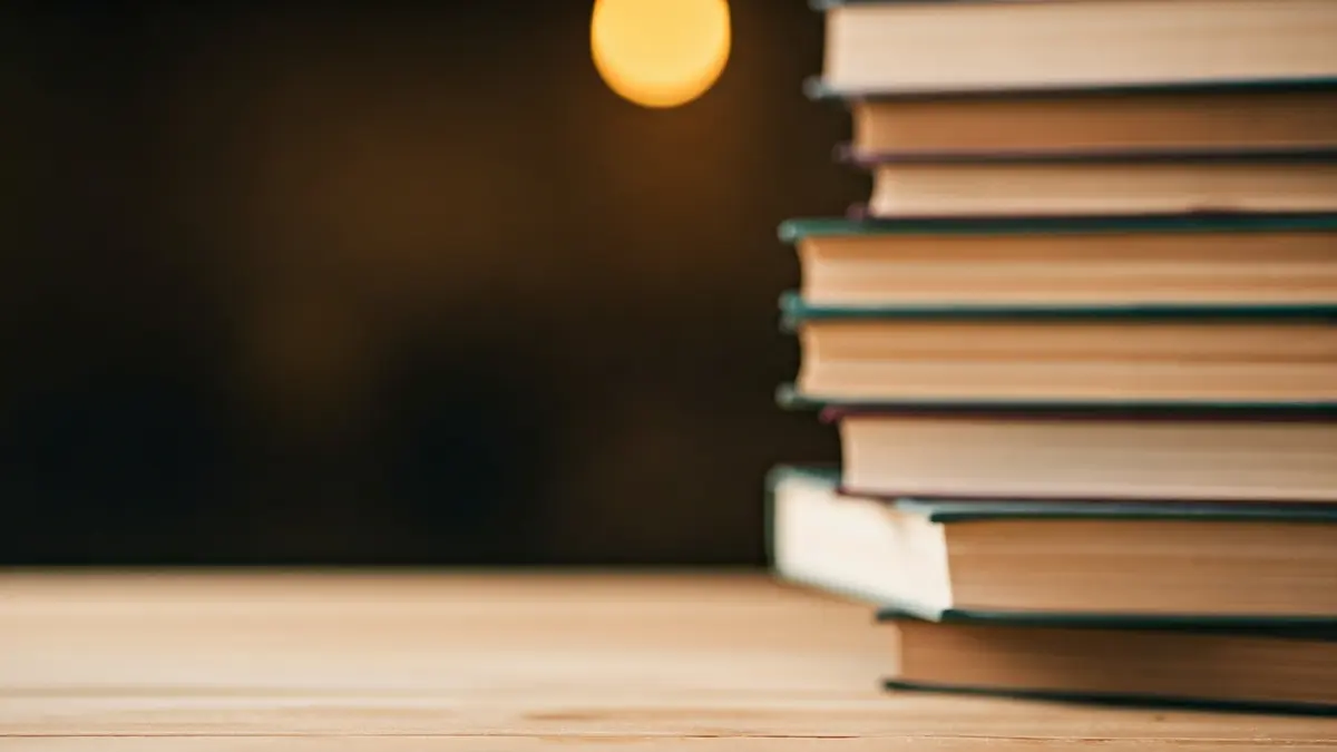 Imatge genèrica de llibres antics sobre una taula de fusta, amb llum càlida.