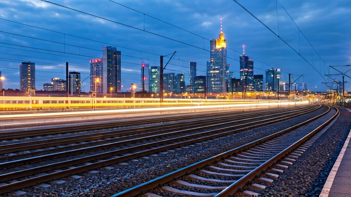 Imatge genèrica de vies de tren d'alta velocitat que s'endinsen en una ciutat al capvespre.