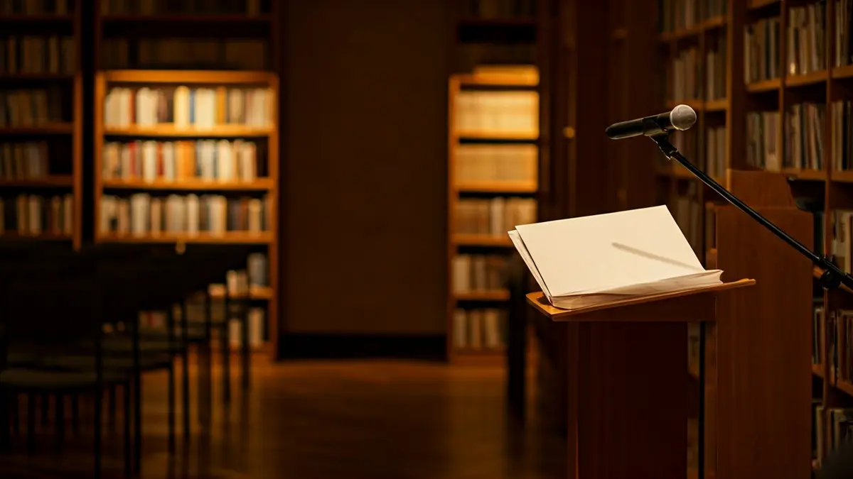 Generic image of a presentation hall or library with a podium and empty chairs.