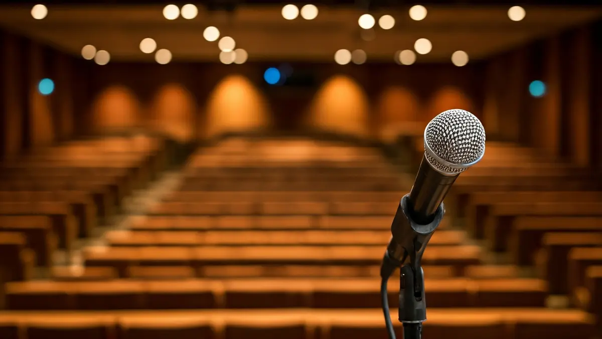 Imatge genèrica d'un micròfon en un faristol en un auditori universitari buit.