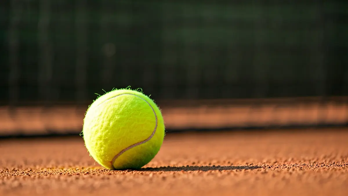 Imatge genèrica d'una pilota de tennis sobre una pista de terra batuda.