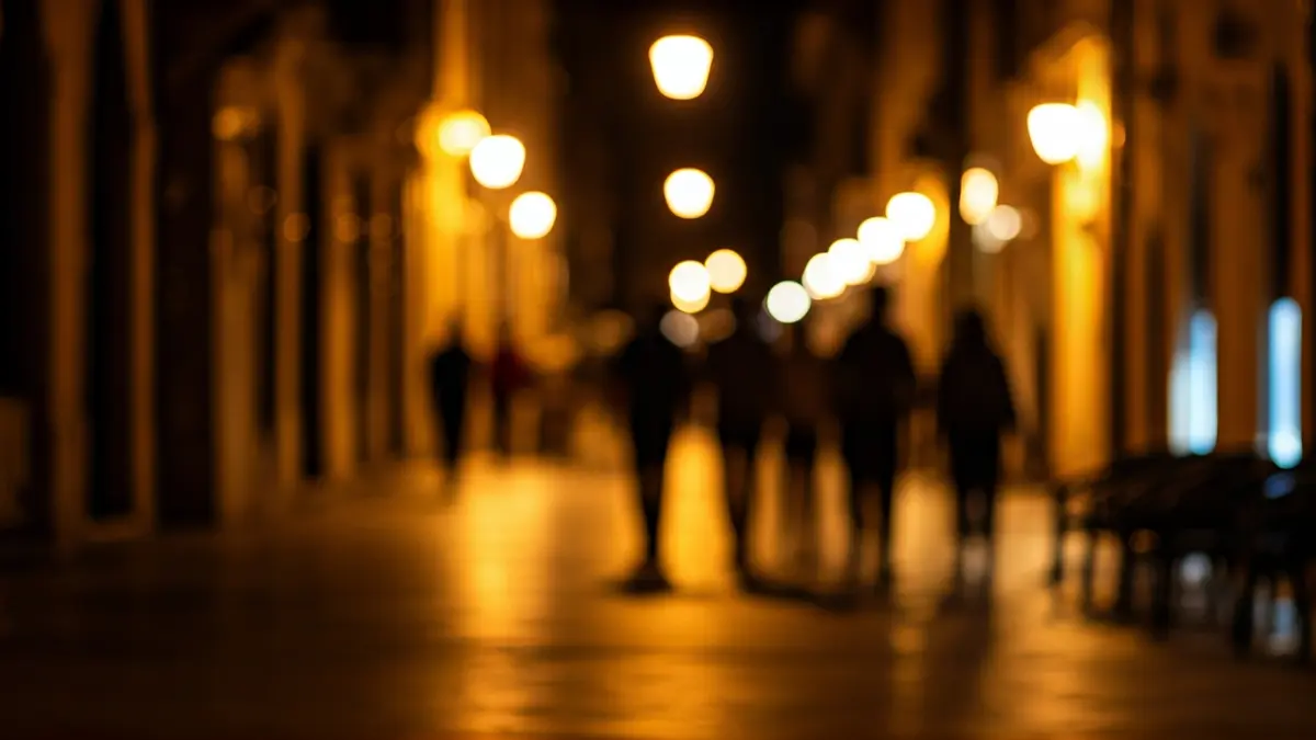 Generic image of a street at night with lights and blurred figures.