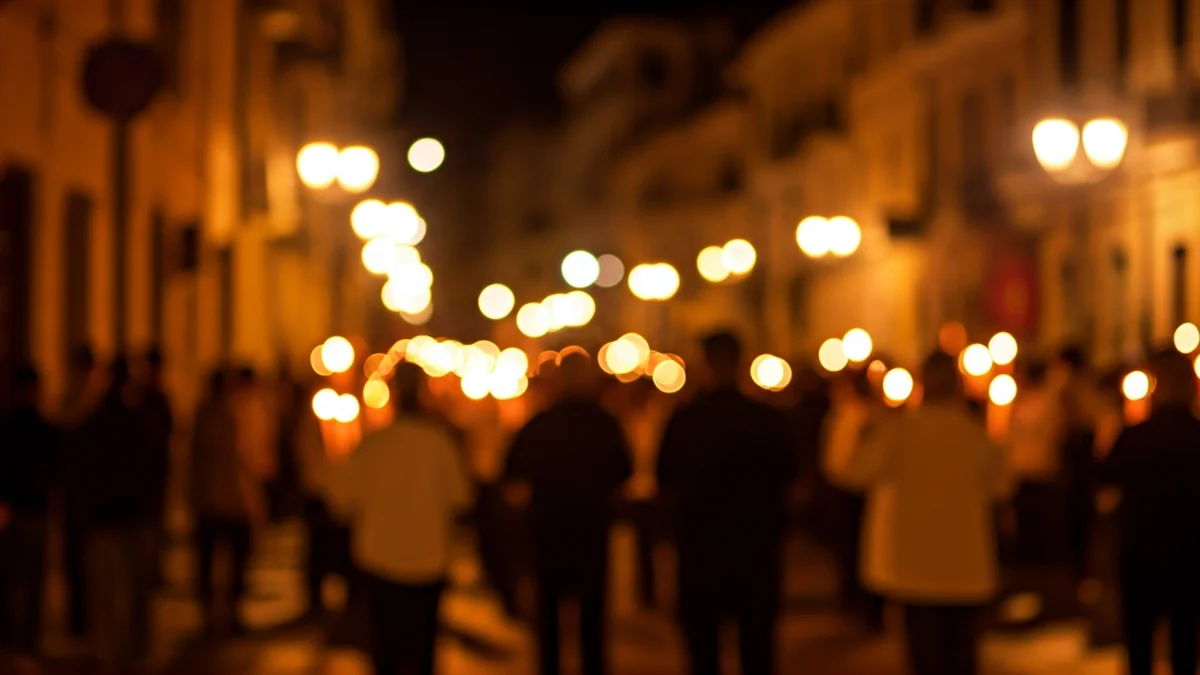 Imatge genèrica d'una processó nocturna amb espelmes en un carrer de ciutat mediterrània.