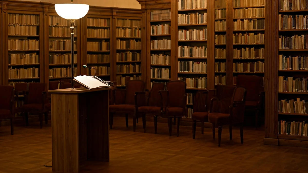 Imagen genérica de una sala de conferencias o biblioteca con un micrófono